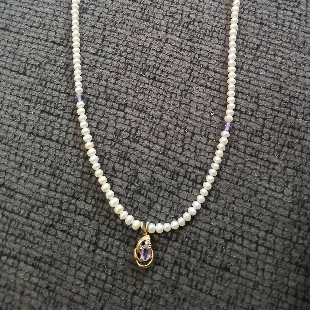 A pearl necklace with a purple diamond